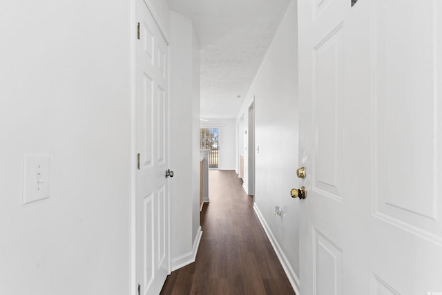 corridor featuring a textured ceiling and dark hardwood / wood-style flooring