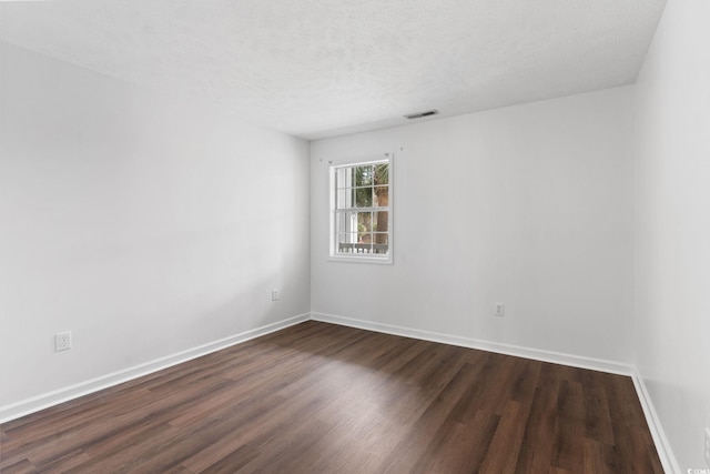 empty room featuring dark wood-type flooring and a textured ceiling