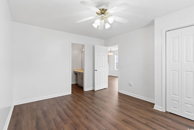 unfurnished bedroom featuring ceiling fan, ensuite bathroom, dark hardwood / wood-style flooring, and a closet