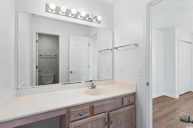 bathroom with vanity, hardwood / wood-style floors, and toilet