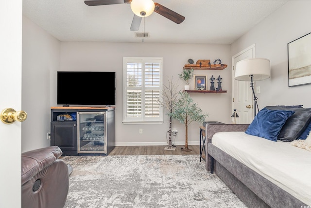 living room with baseboards, ceiling fan, visible vents, and wood finished floors