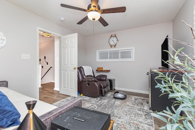 bedroom featuring baseboards, a textured ceiling, ceiling fan, and wood finished floors