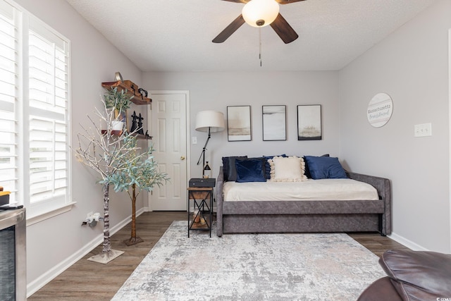 living area with baseboards, plenty of natural light, ceiling fan, and wood finished floors