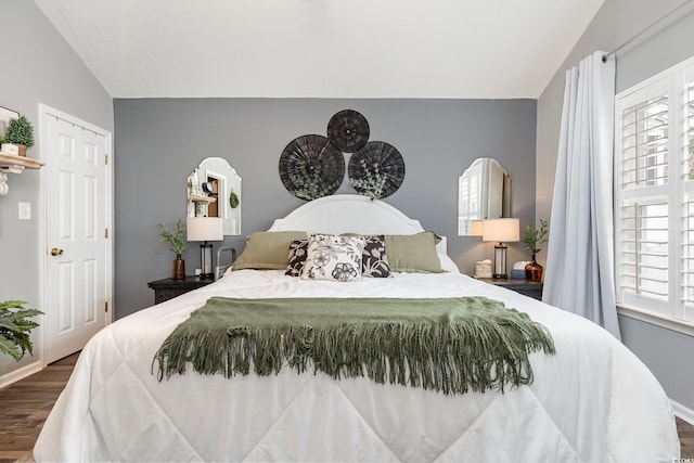 bedroom featuring baseboards, vaulted ceiling, multiple windows, and wood finished floors