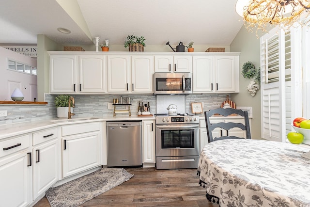 kitchen with a sink, appliances with stainless steel finishes, dark wood finished floors, and white cabinetry