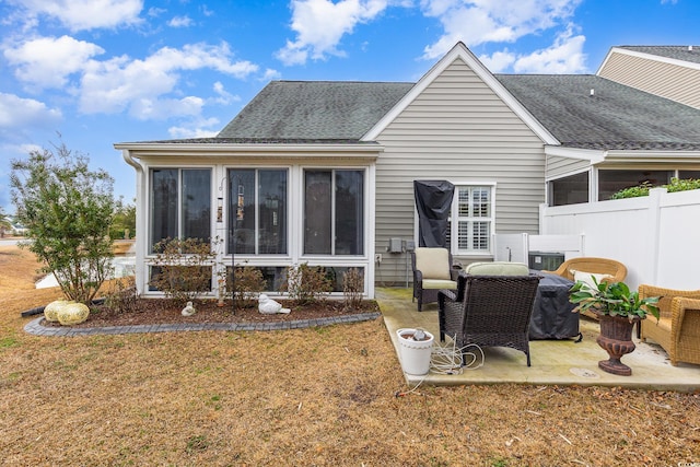 rear view of property with a lawn, a shingled roof, a patio area, and a sunroom