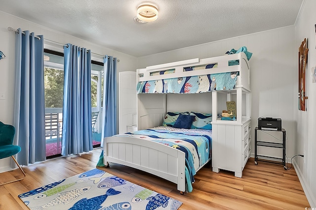 bedroom with crown molding, wood-type flooring, a textured ceiling, and access to outside