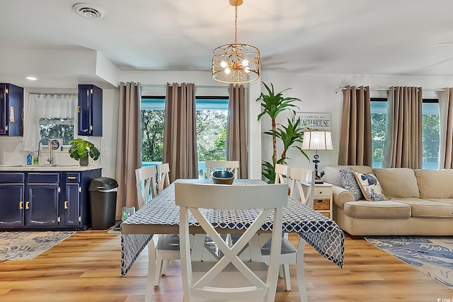 dining space featuring sink, a notable chandelier, and light wood-type flooring