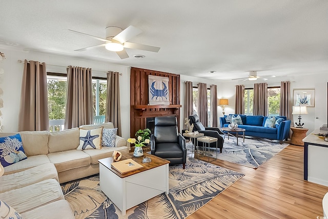 living room with a textured ceiling, light hardwood / wood-style flooring, ceiling fan, and plenty of natural light