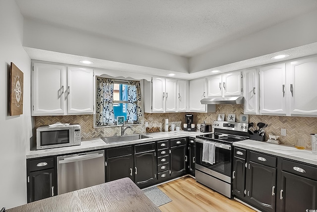 kitchen featuring sink, a textured ceiling, light hardwood / wood-style flooring, stainless steel appliances, and white cabinets