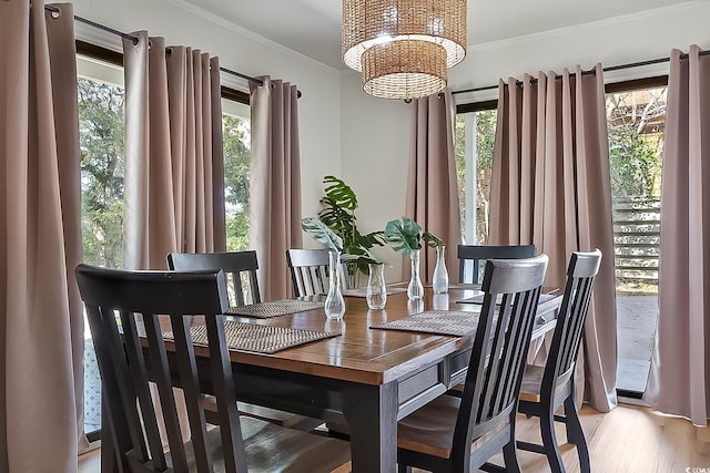 dining area with an inviting chandelier, plenty of natural light, crown molding, and light wood-type flooring