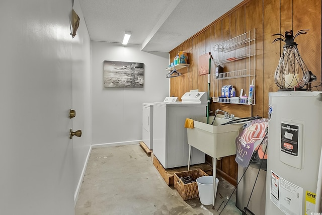 laundry area featuring washer and dryer, wood walls, water heater, sink, and a textured ceiling