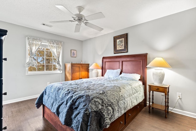 bedroom with ceiling fan, dark hardwood / wood-style floors, and a textured ceiling