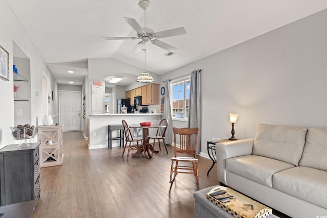 living room with hardwood / wood-style flooring, ceiling fan, lofted ceiling, and a textured ceiling