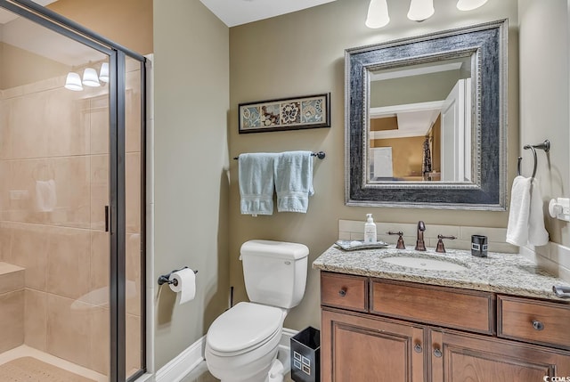bathroom featuring vanity, baseboards, a stall shower, and toilet