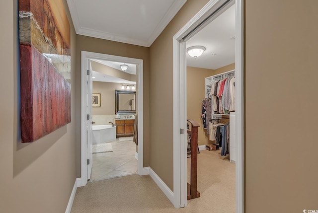 hall featuring crown molding, baseboards, and light carpet