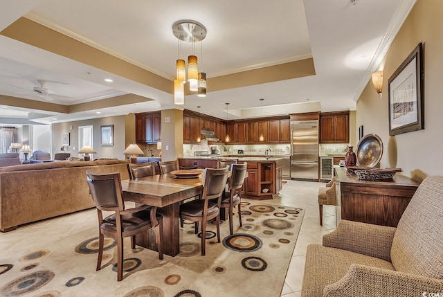 dining area featuring a ceiling fan, a tray ceiling, ornamental molding, and light tile patterned floors
