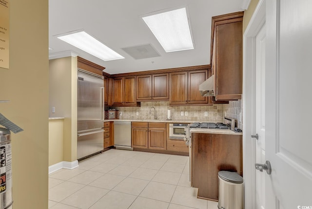 kitchen with a sink, appliances with stainless steel finishes, backsplash, and light countertops