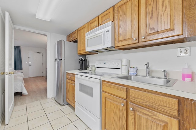 kitchen with sink, light tile patterned floors, and white appliances