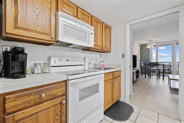 kitchen with light tile patterned flooring, sink, ceiling fan, and white appliances