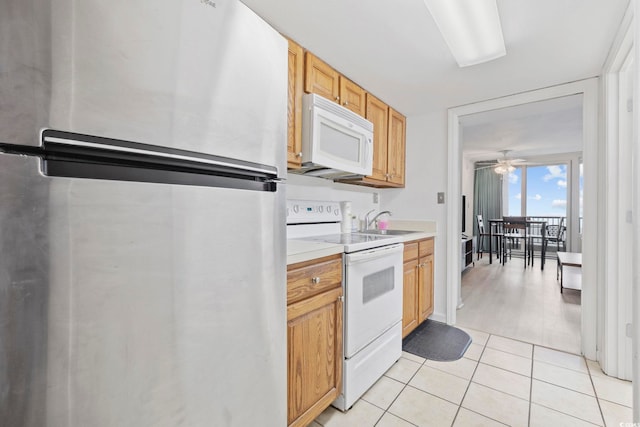 kitchen with light tile patterned floors, white appliances, sink, and ceiling fan