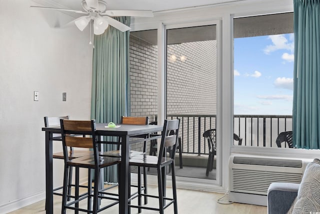 dining room with a wall mounted AC, ceiling fan, and light wood-type flooring