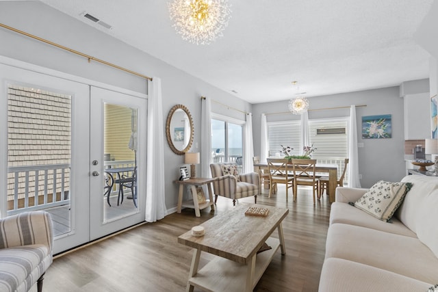 living room featuring an inviting chandelier, dark wood-type flooring, french doors, and a textured ceiling