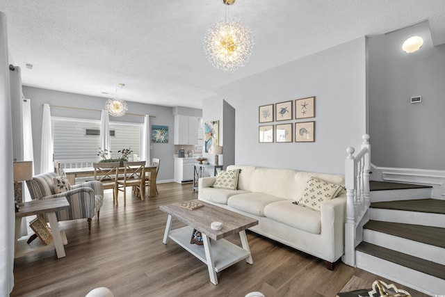 living room featuring an inviting chandelier, dark hardwood / wood-style floors, and a textured ceiling