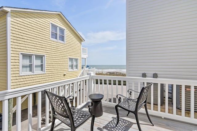 wooden deck featuring a water view and a beach view