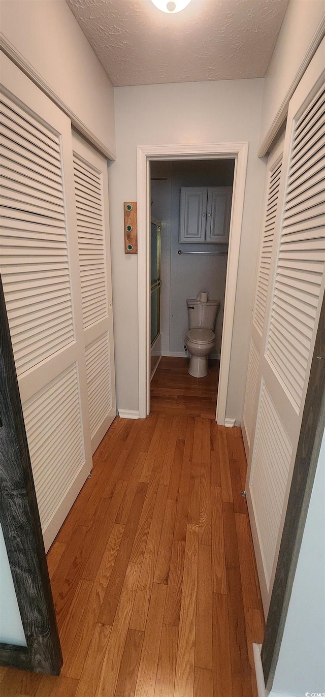 hallway with hardwood / wood-style flooring and a textured ceiling