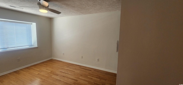 unfurnished room with ceiling fan, a textured ceiling, and light wood-type flooring