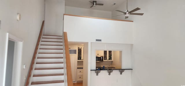 stairway with a towering ceiling and ceiling fan