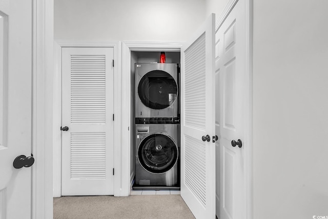 clothes washing area with stacked washer and clothes dryer and light carpet