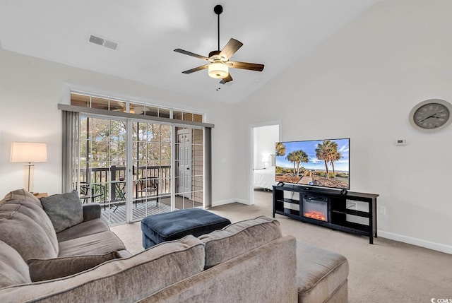 carpeted living room with ceiling fan and high vaulted ceiling