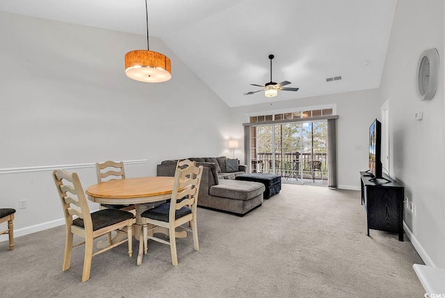 dining area with high vaulted ceiling, light carpet, and ceiling fan