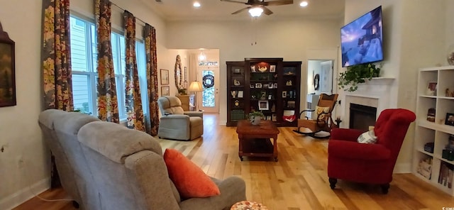 living room featuring ceiling fan, a high ceiling, and light wood-type flooring