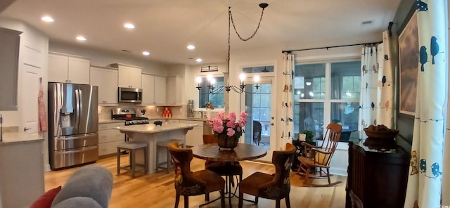 kitchen featuring pendant lighting, light hardwood / wood-style flooring, white cabinetry, stainless steel appliances, and a center island