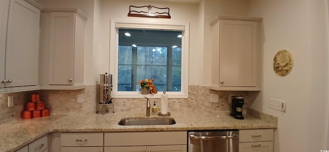 kitchen featuring light stone countertops, sink, stainless steel dishwasher, and white cabinets