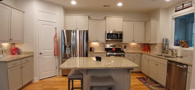 kitchen featuring a kitchen bar, stainless steel appliances, white cabinets, and a kitchen island