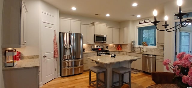 kitchen featuring a kitchen island, sink, a kitchen bar, stainless steel appliances, and light stone countertops