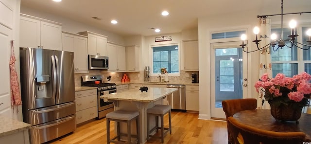 kitchen with pendant lighting, appliances with stainless steel finishes, a kitchen island, and white cabinets