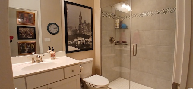 bathroom with a shower with door, vanity, and toilet