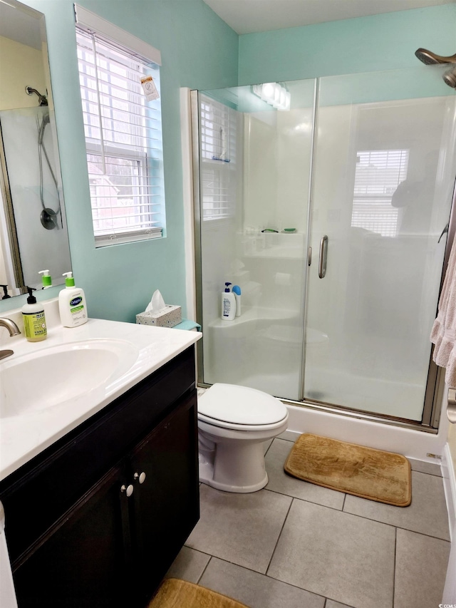 bathroom featuring walk in shower, vanity, toilet, and tile patterned flooring