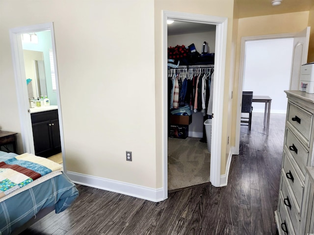 bedroom with dark wood-type flooring, connected bathroom, a closet, and a spacious closet