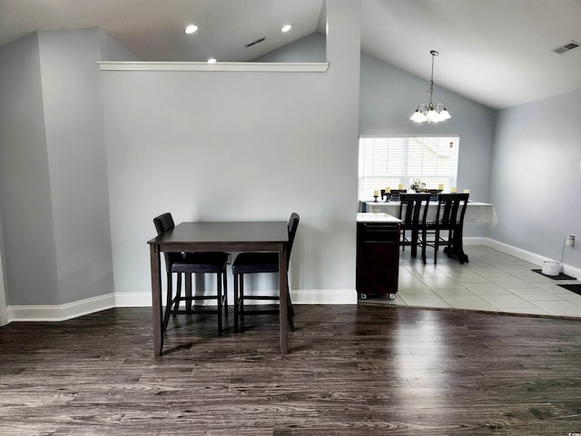 dining room featuring an inviting chandelier, wood-type flooring, and vaulted ceiling