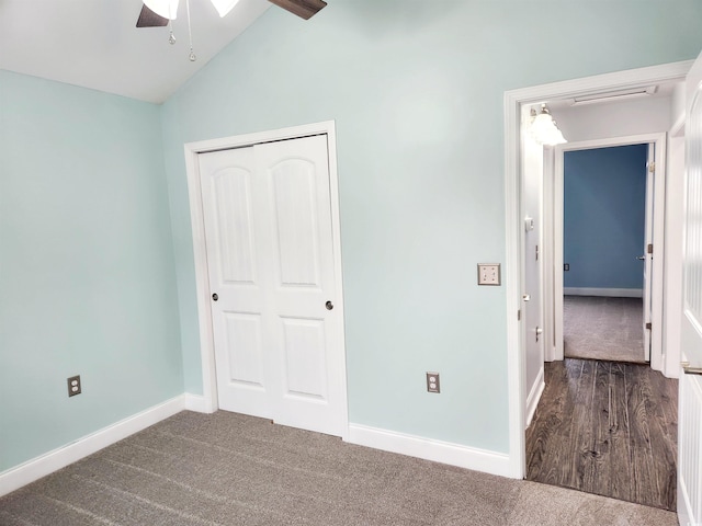 unfurnished bedroom with lofted ceiling, dark carpet, and a closet