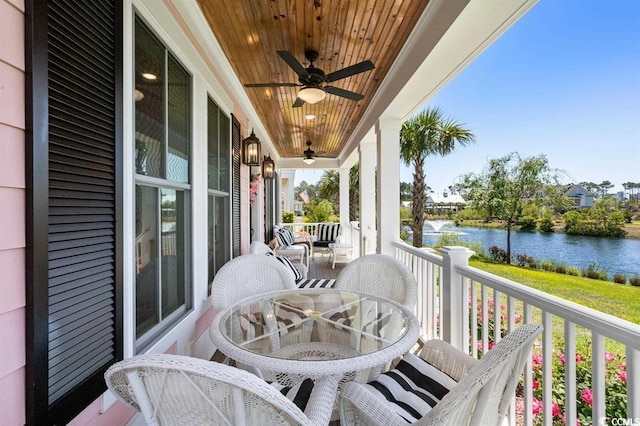 balcony featuring a water view, covered porch, and ceiling fan