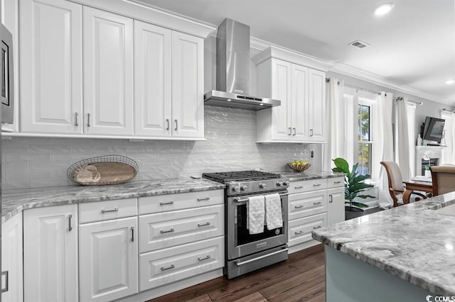 kitchen with crown molding, appliances with stainless steel finishes, wall chimney range hood, and white cabinets