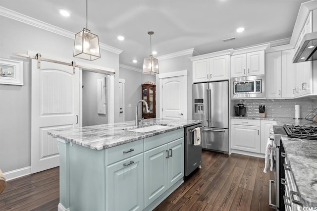 kitchen featuring sink, high end appliances, a barn door, a kitchen island with sink, and white cabinets