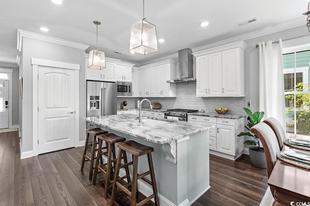 kitchen with wall chimney exhaust hood, high quality appliances, sink, and white cabinets